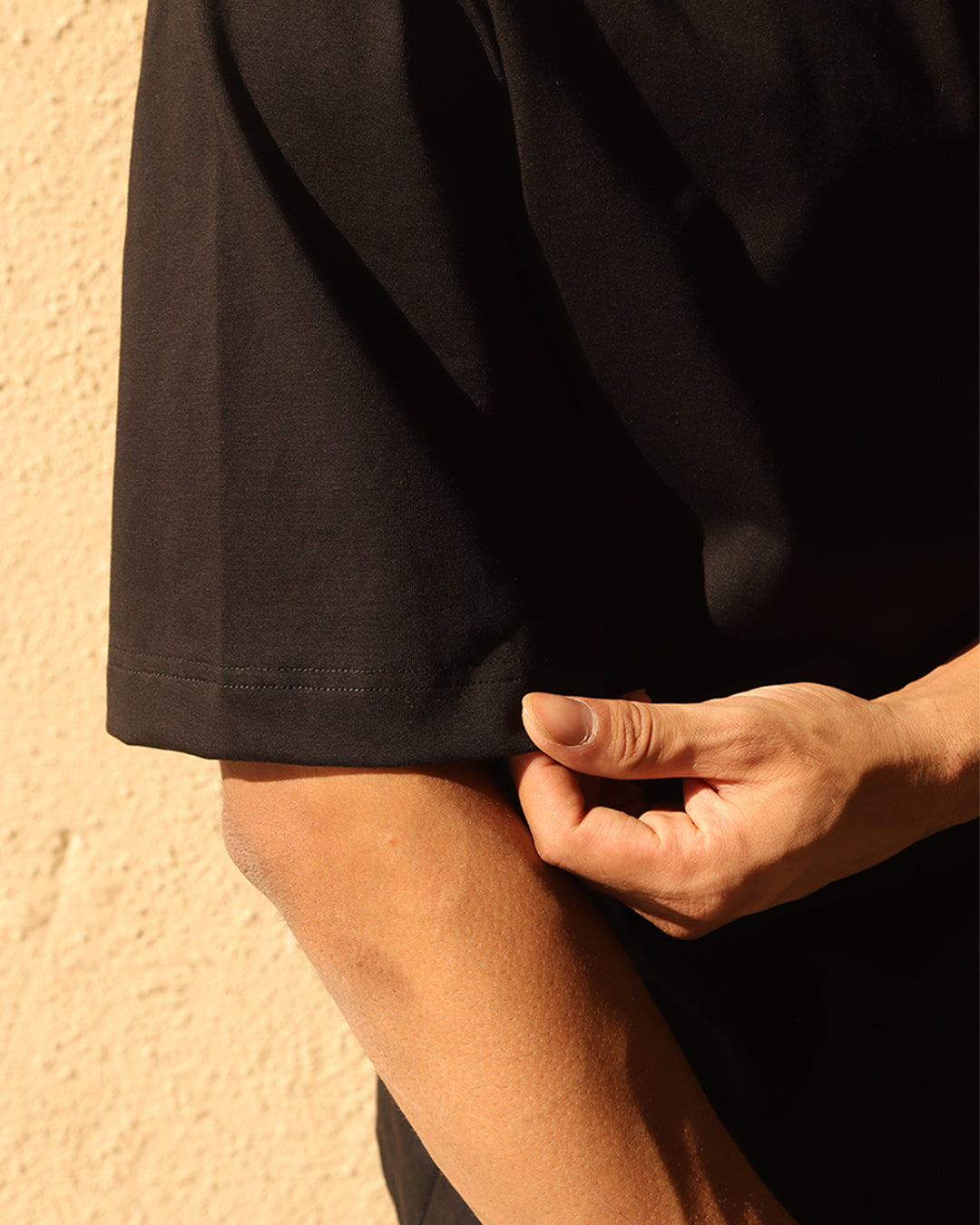 Man wearing black tshirt showing sleeves and stitches in it