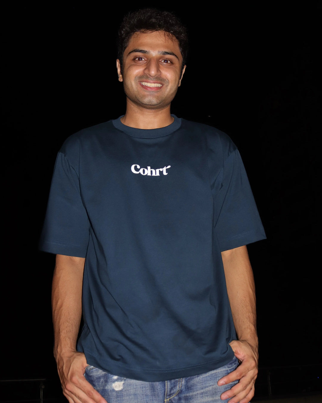 Man standing wearing a dark blue t-shirt, With Cohrt written in the front and "Cause you're a sky full of stars" written on the back.