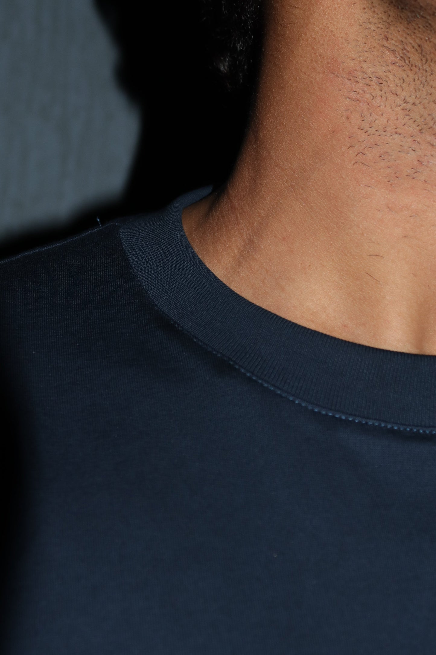 Man standing wearing a dark blue t-shirt, showing great stitches
