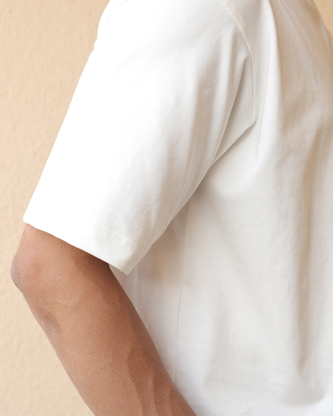 Man wearing white tshirt showing his sleeves and his stitches
