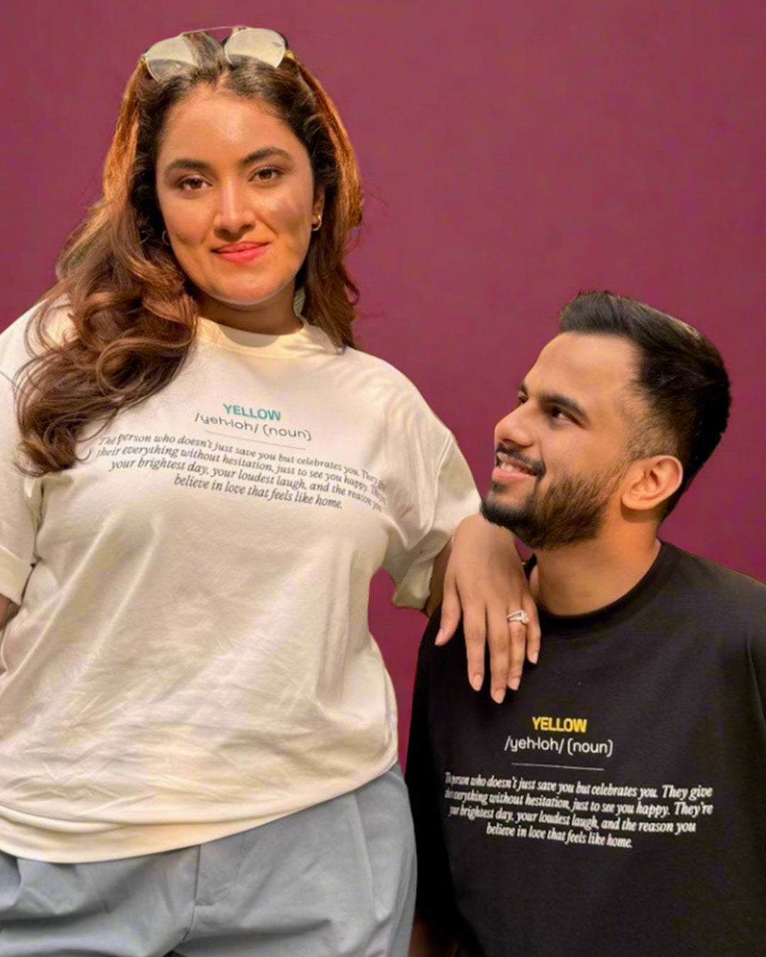 Man and Woman, sitting and standing wearing a black and White t-shirt, with Yellow and its meaning written in the front