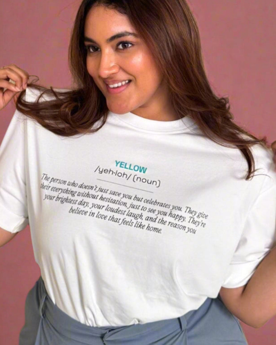 Woman standing wearing a White t-shirt, with yellow and its meaning written in the front