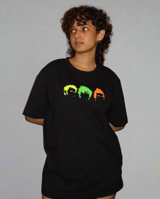 woman wearing black tshirt with three head/hair outlines in the front , in the colour yellow green and orange 