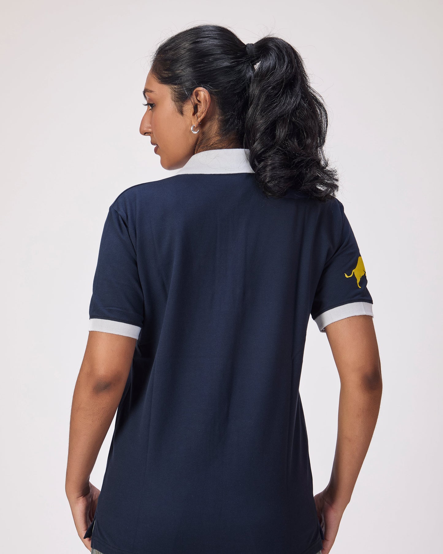 Person wearing a navy blue polo shirt with a logo on the sleeve against a white background