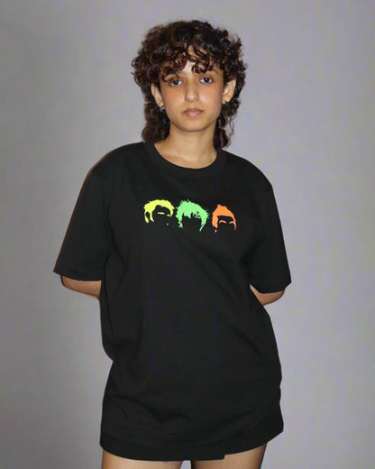 woman wearing black tshirt with three head/hair outlines in the front , in the colour yellow green and orange 