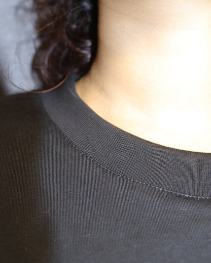 woman showcasing her tshirts neck and the stitches in t , wearing a black tshirt