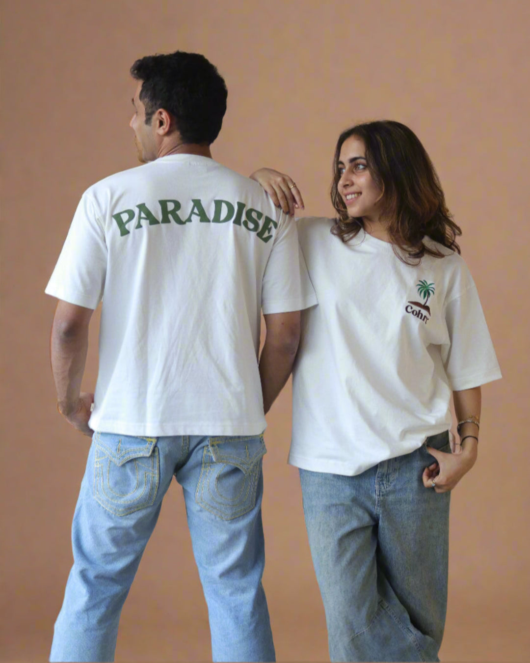 Woman and man standing Wearing white t-shirt and Palm tree on the pocket side and pardise written on the back