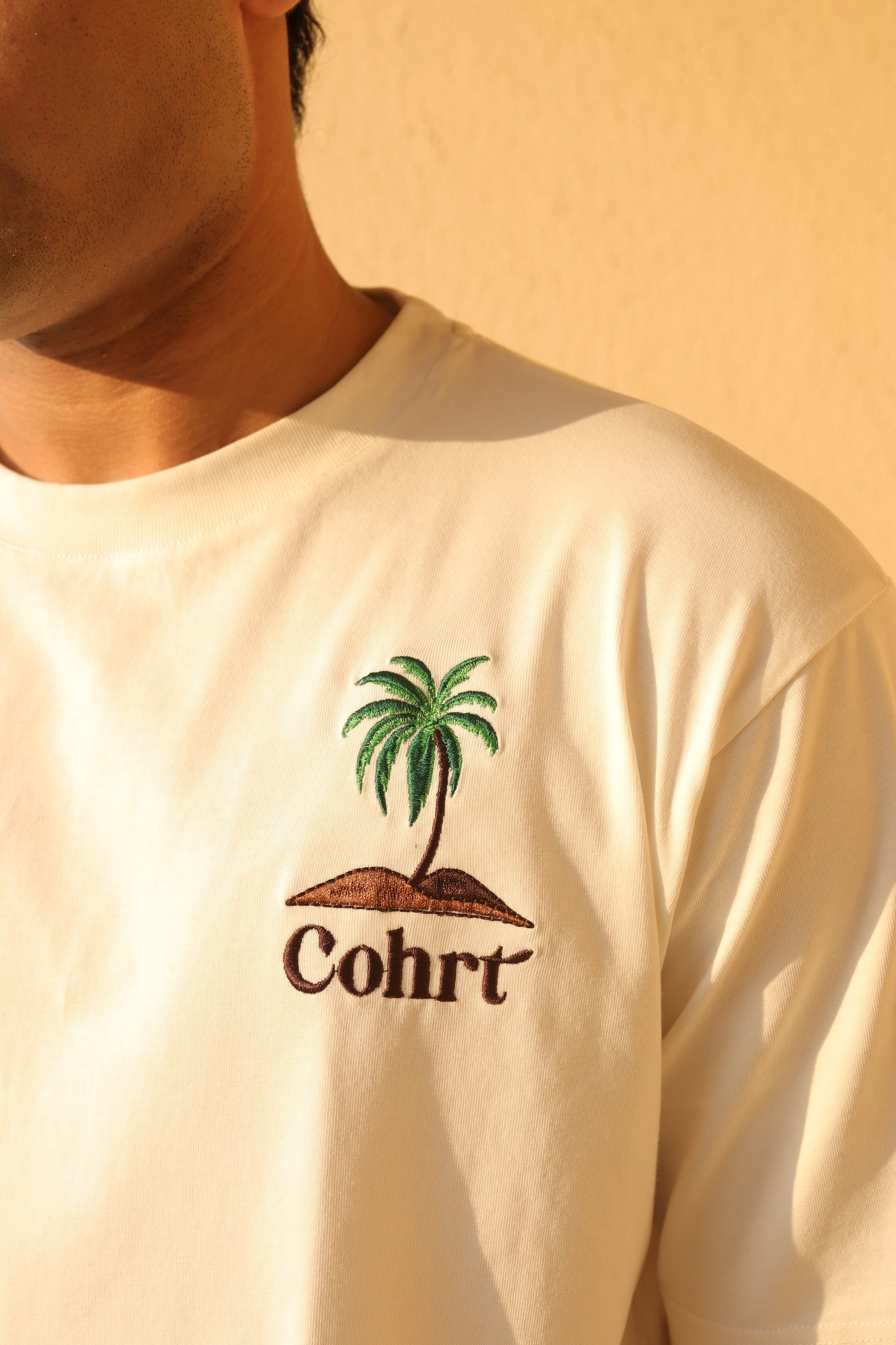 Man standing Wearing white t-shirt and Palm tree on the pocket side 