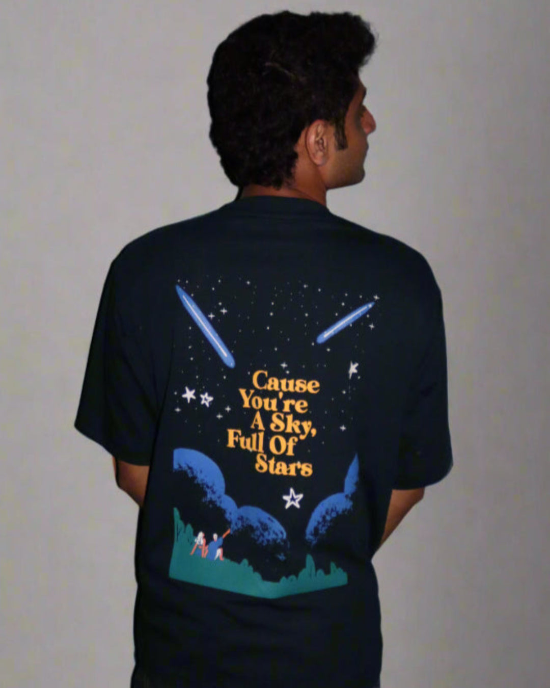 Man standing wearing a dark blue t-shirt, With Cohrt written in the front   and "Cause you're a sky full of stars" written on the back.