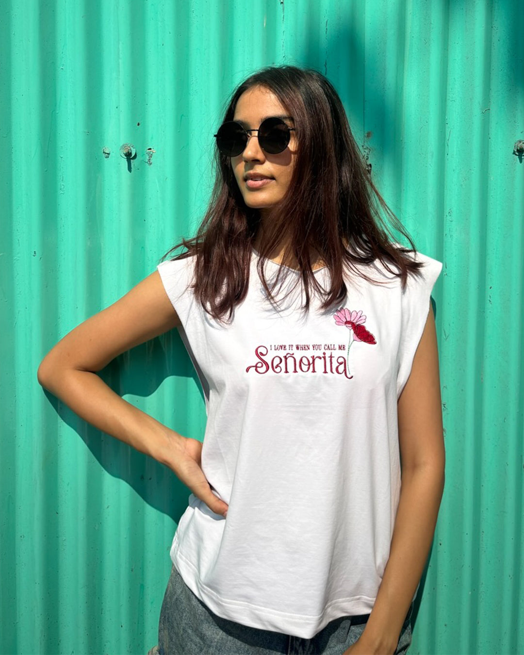 woman wearing white tank top with i love it when you call me senorita embroided on the front
