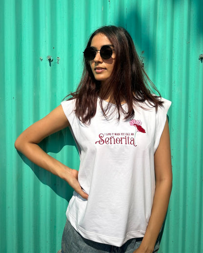 woman wearing white tank top with i love it when you call me senorita embroided on the front