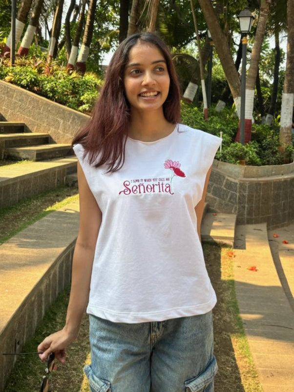 woman wearing white tank top with i love it when you call me senorita embroided on the front
